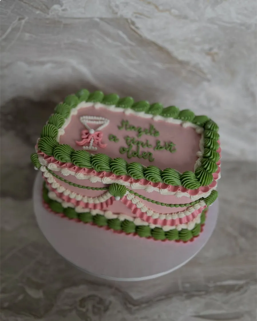 Pink and green retro birthday cake with a piped martini glass